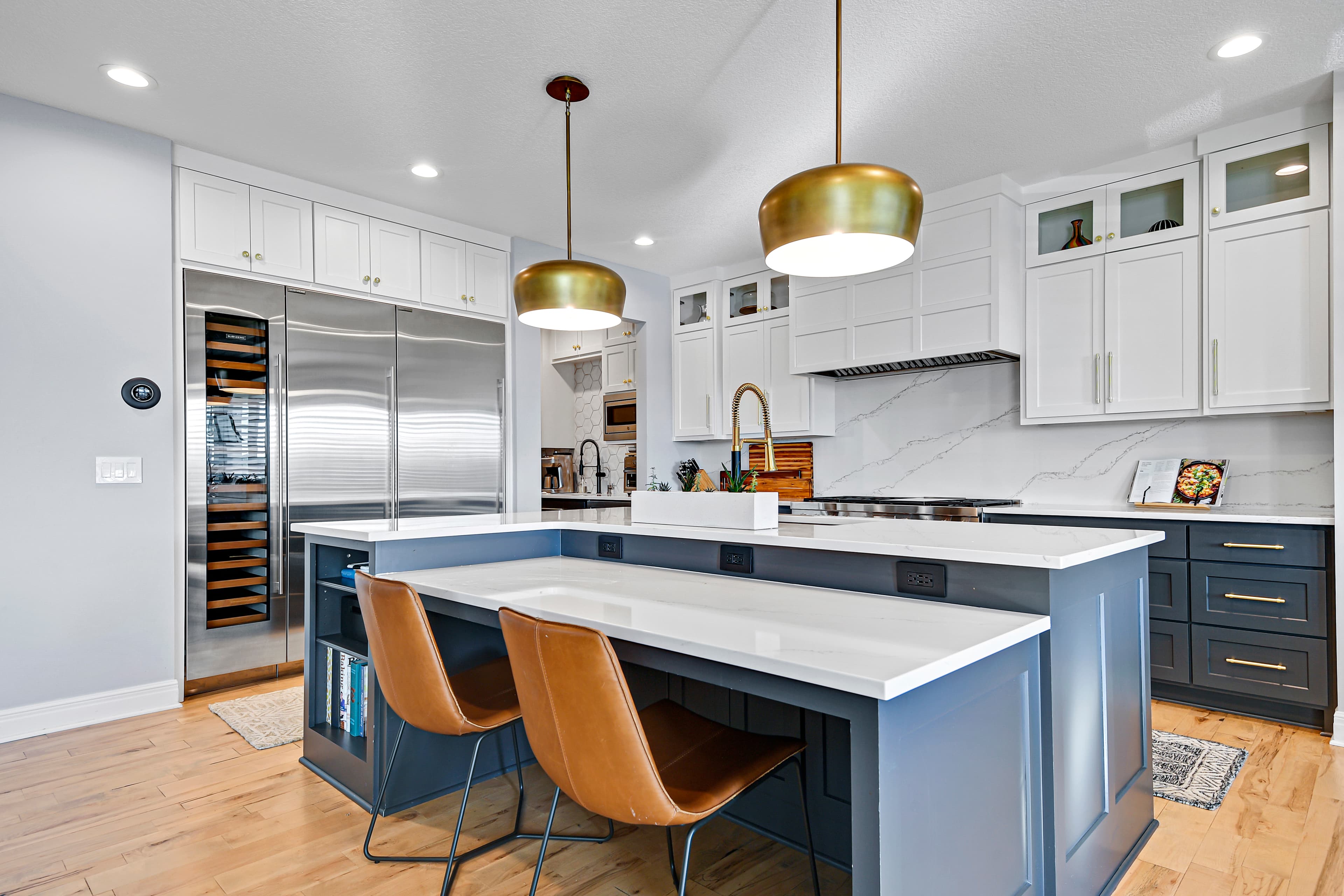 Kitchen with a deep blue island and brass pendants