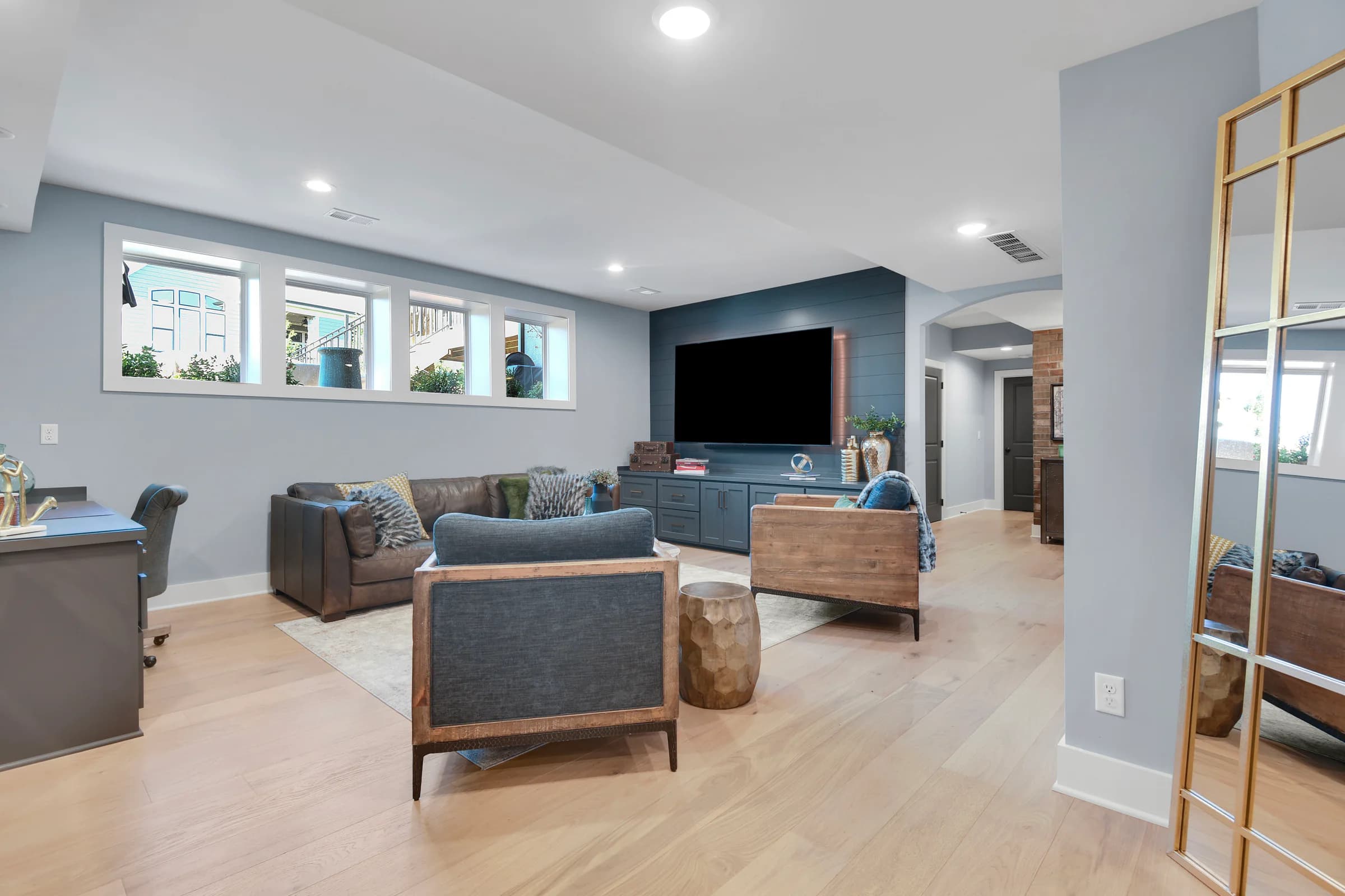 Professionally styled living room with layered seating, a deep blue media wall, and warm wood details