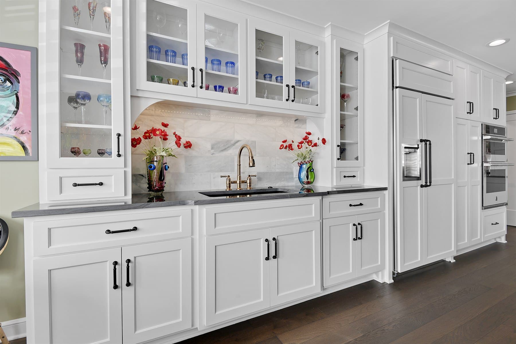 White custom kitchen styled with colorful glassware and red floral accents