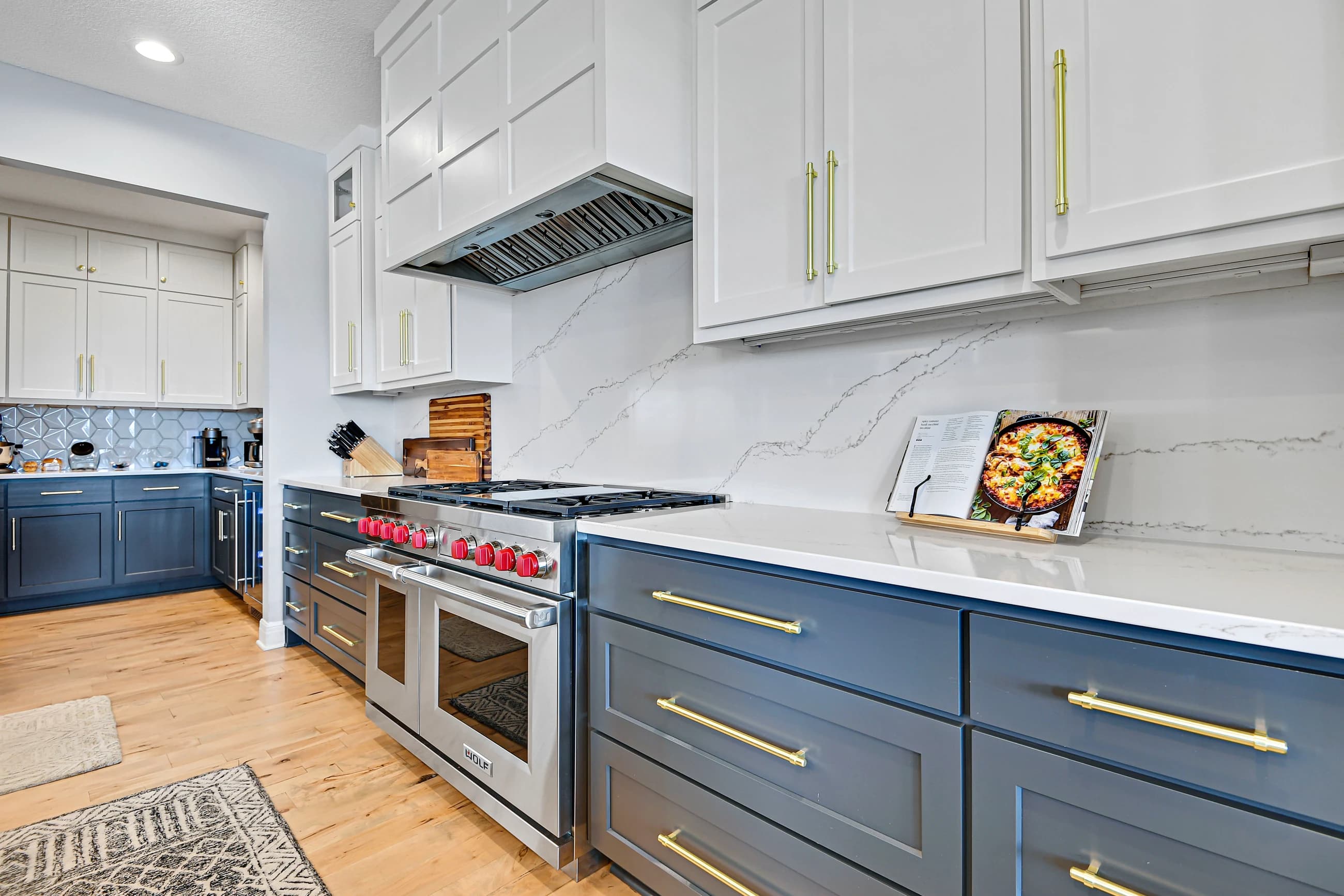 Cohesive custom kitchen with coordinated navy cabinetry, white finishes, lighting, and hardware