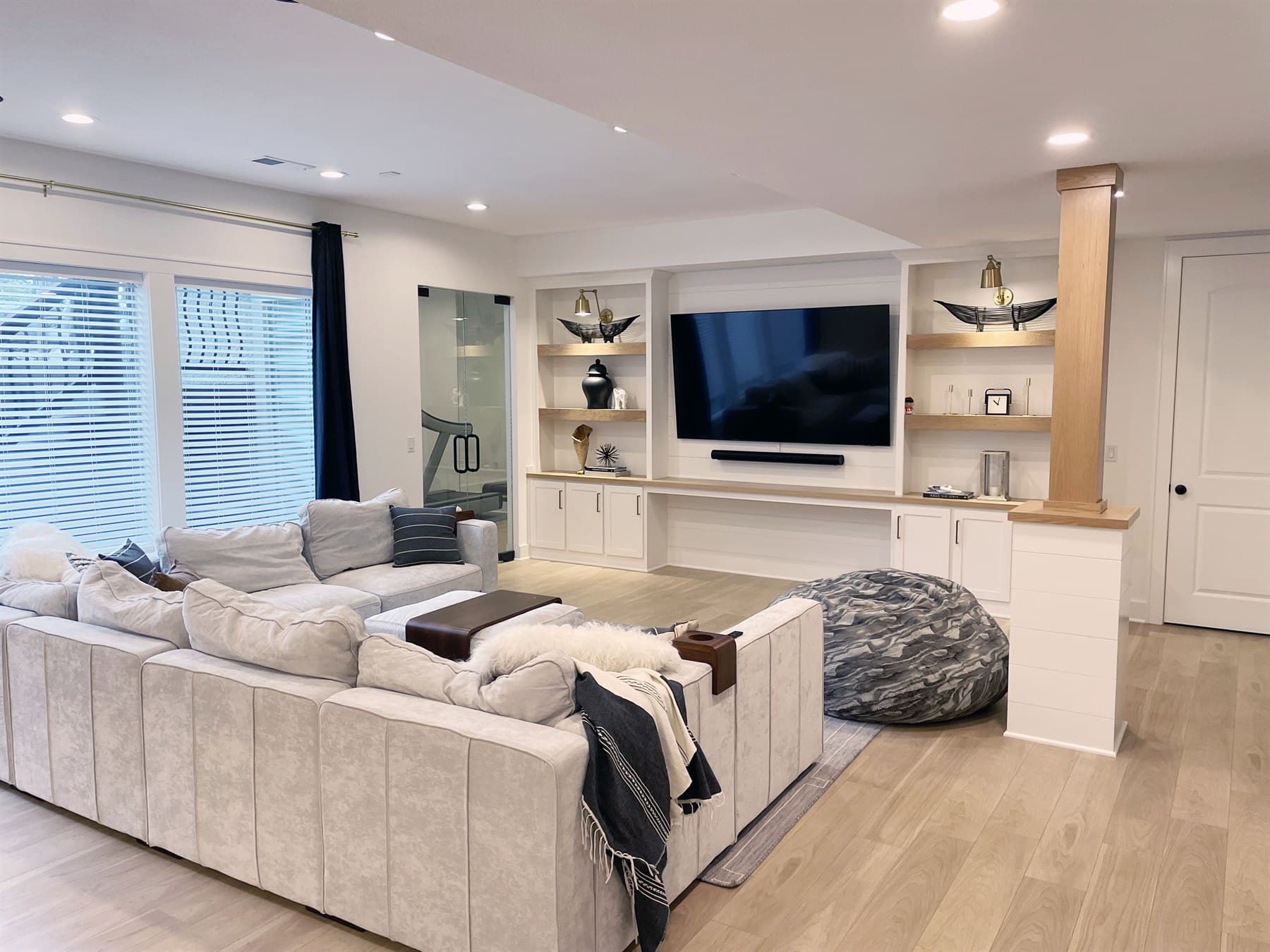 Modern family room staged with a large sectional, built-in media wall, and warm wood details