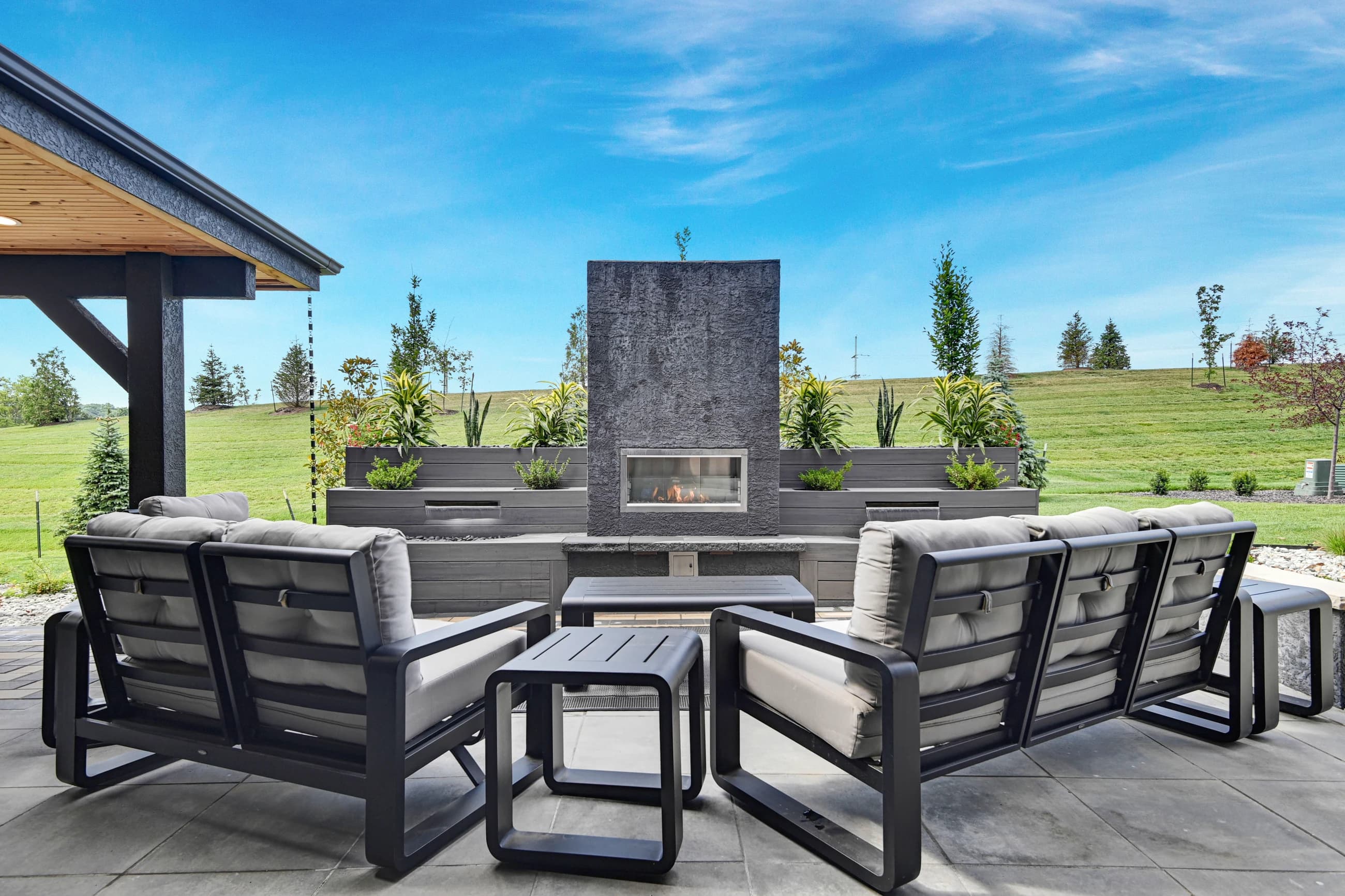 Covered outdoor lounge staged around a modern fireplace with coordinated seating